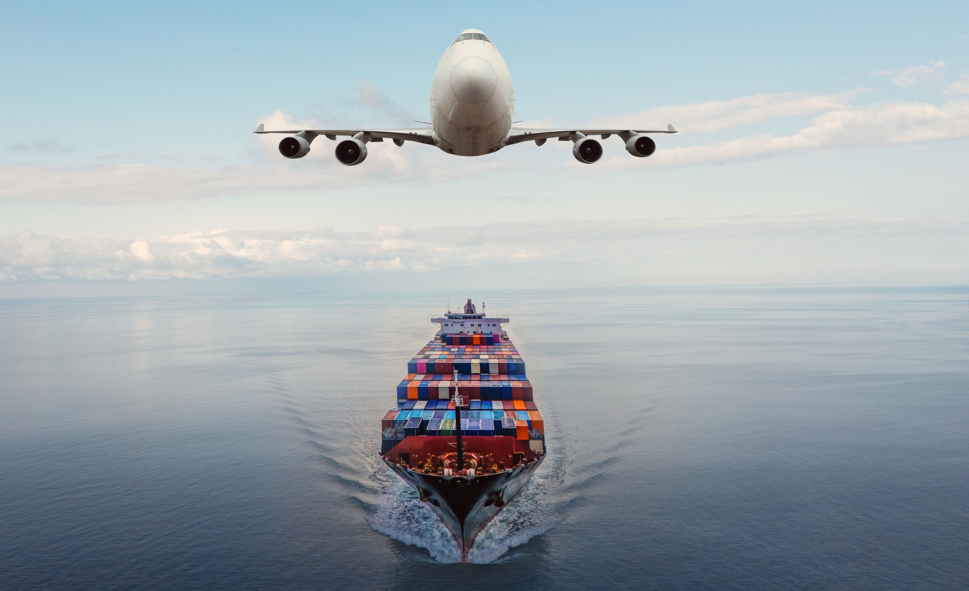 Cargo Airplane flying above container ship.